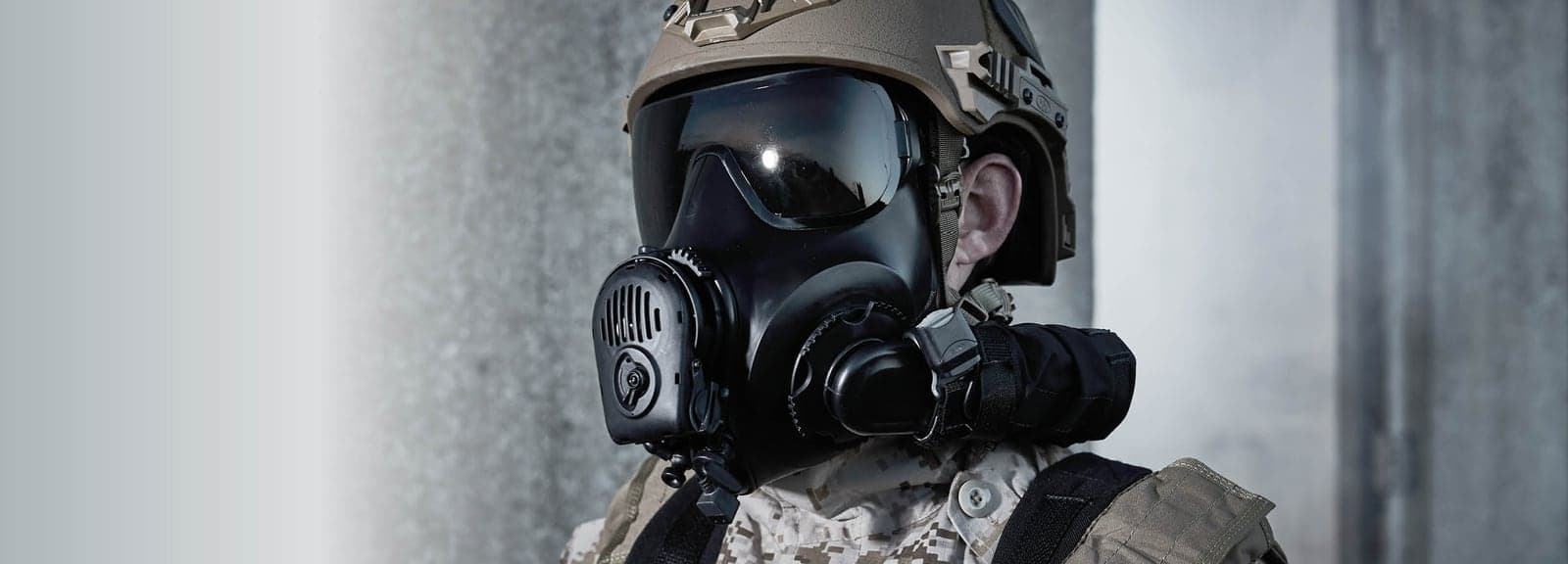 Soldier in a helmet wearing a black Avon FM53 mask with a side-mounted filter