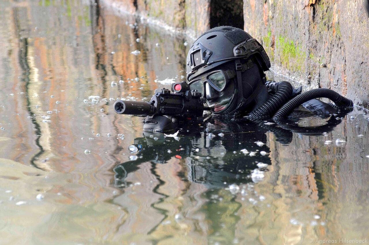Combat swimmer emerging from water with a suppressed MP7