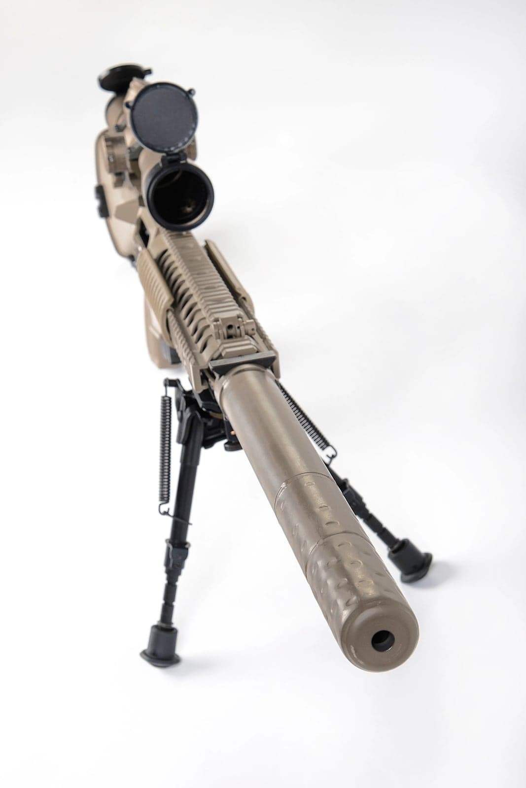 Tan M110 suppressor fitted to an M110 rifle on a bipod, viewed from the muzzle end
