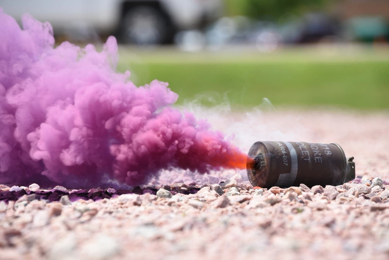 M18 violet smoke grenade burning on gravel during training
