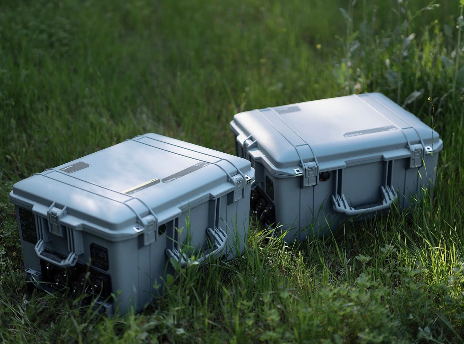 Two closed white Menace-T hard cases side by side on grass