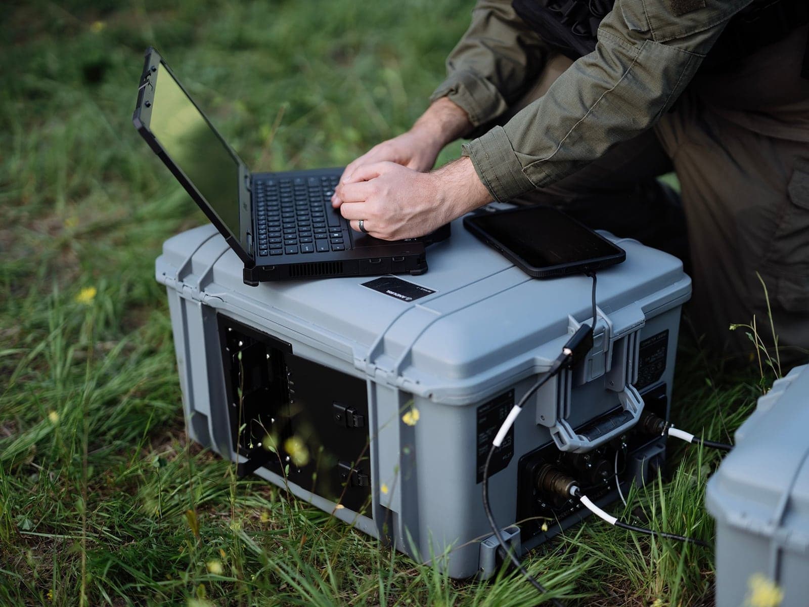 Operator typing on a rugged laptop resting on a sealed Menace-T case