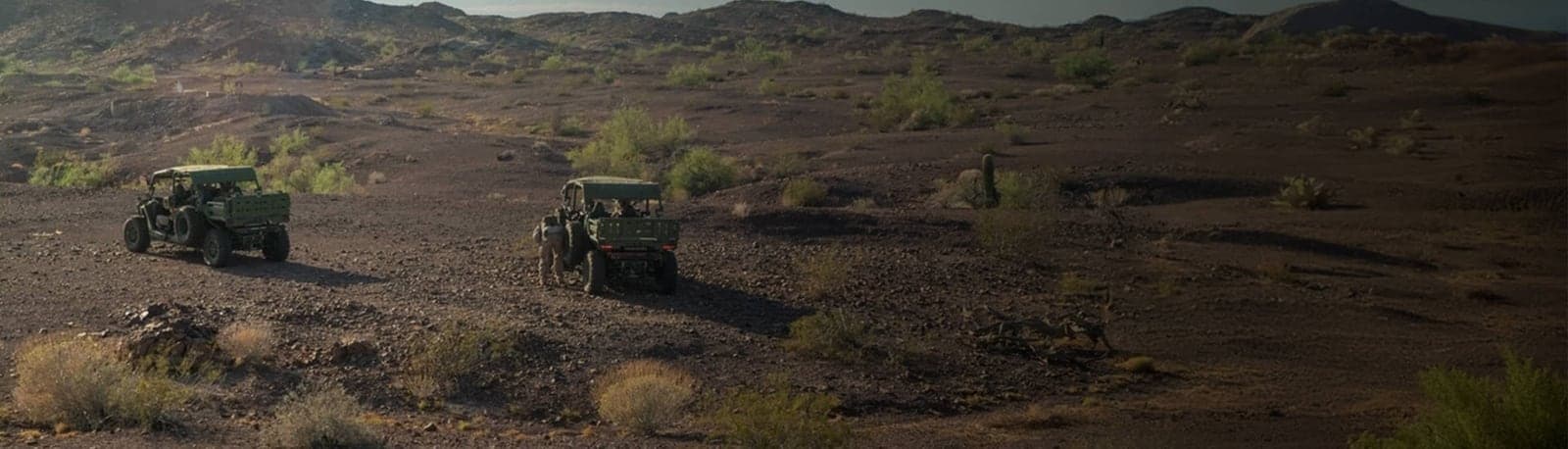 Two MRZR Alpha vehicles crossing dark desert terrain
