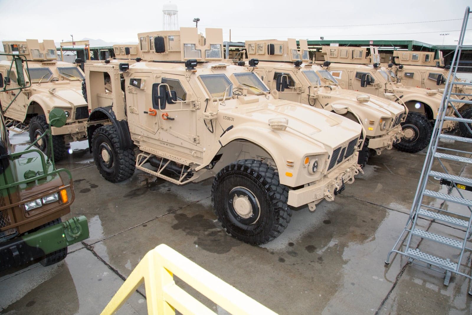 Row of upgraded M-ATVs awaiting road testing at a Marine Corps depot on a rainy day