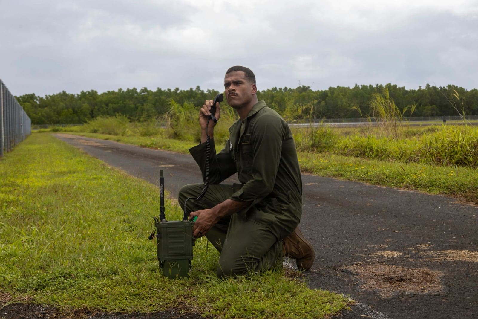 Marine kneeling beside a road with an AN/PRC-160(V) and handset during exercise Slingshot