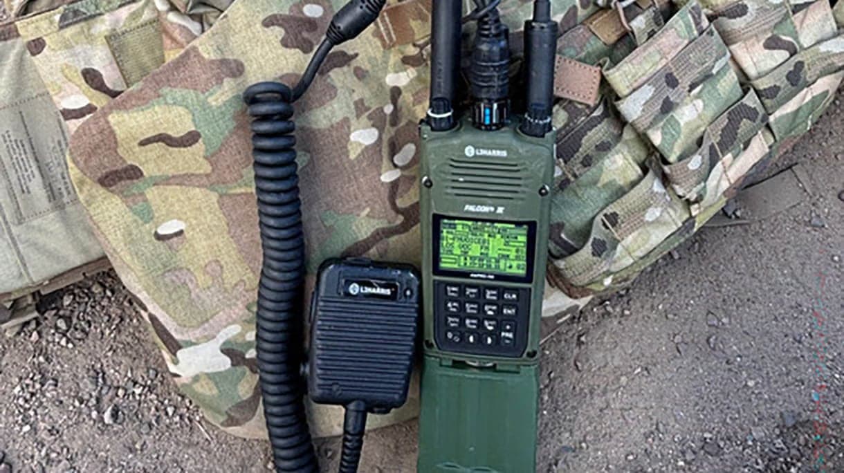 AN/PRC-163 with handset lying on a camouflage vest on the ground