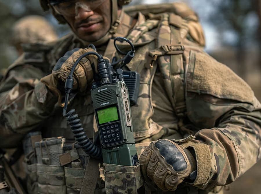 Soldier in camouflage operating an AN/PRC-163 mounted on his chest rig
