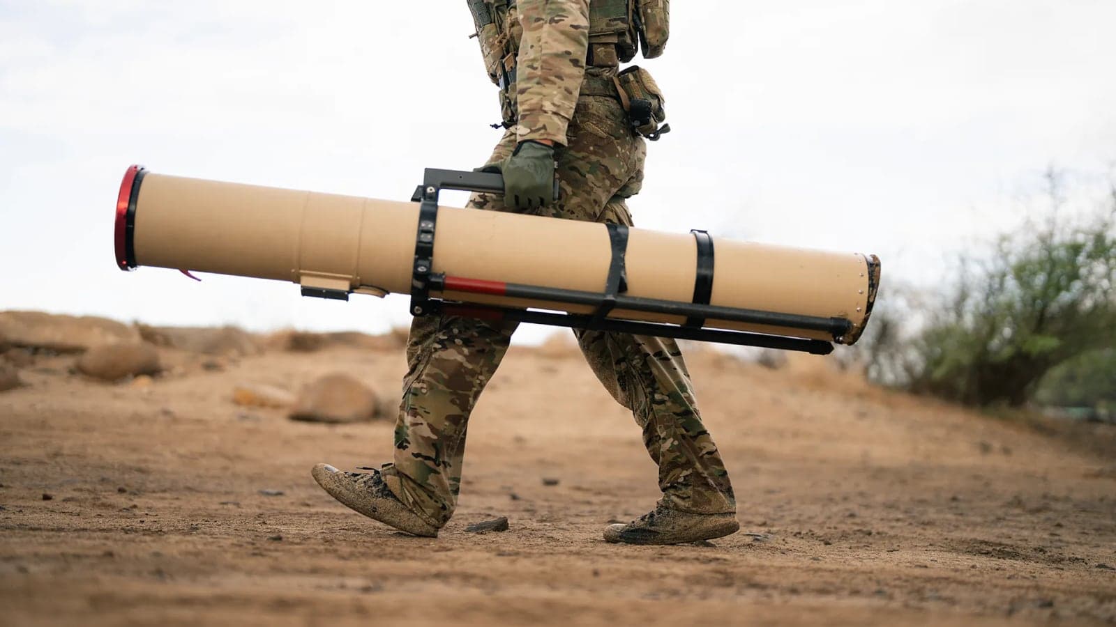 Soldier carrying a Switchblade 600 launch tube across desert ground