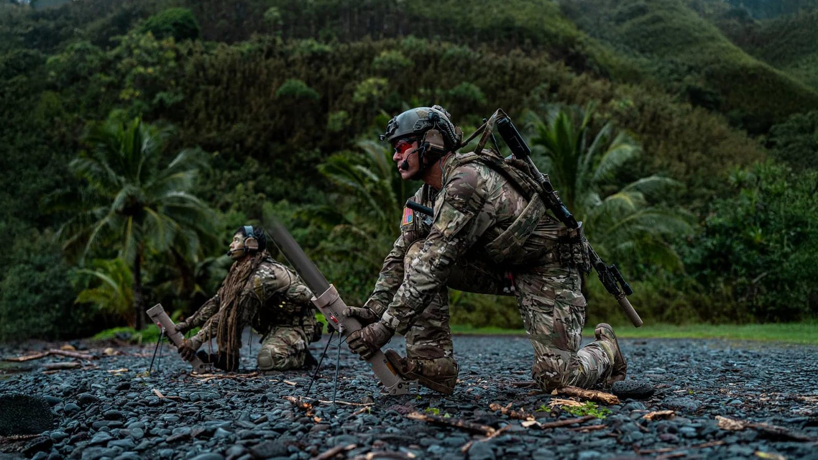 Two soldiers preparing Switchblade 300 tubes for launch in a jungle clearing