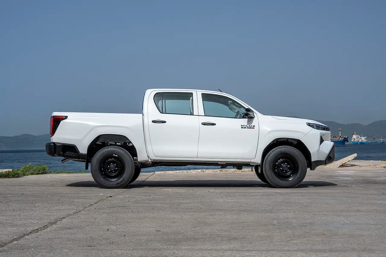 White Hilux Double Cab side profile on a quayside with the sea behind