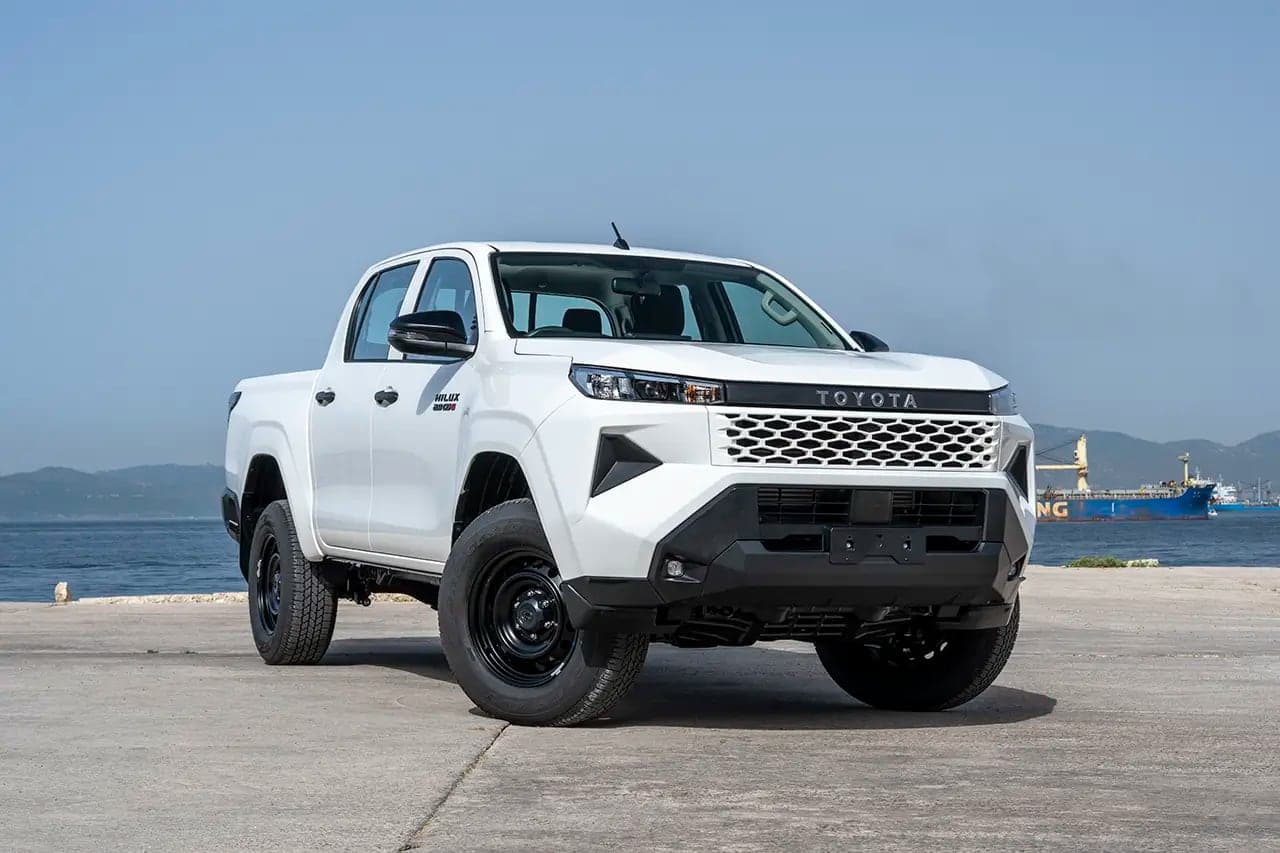 White Toyota Hilux double cab pickup parked on a quayside with the sea behind it