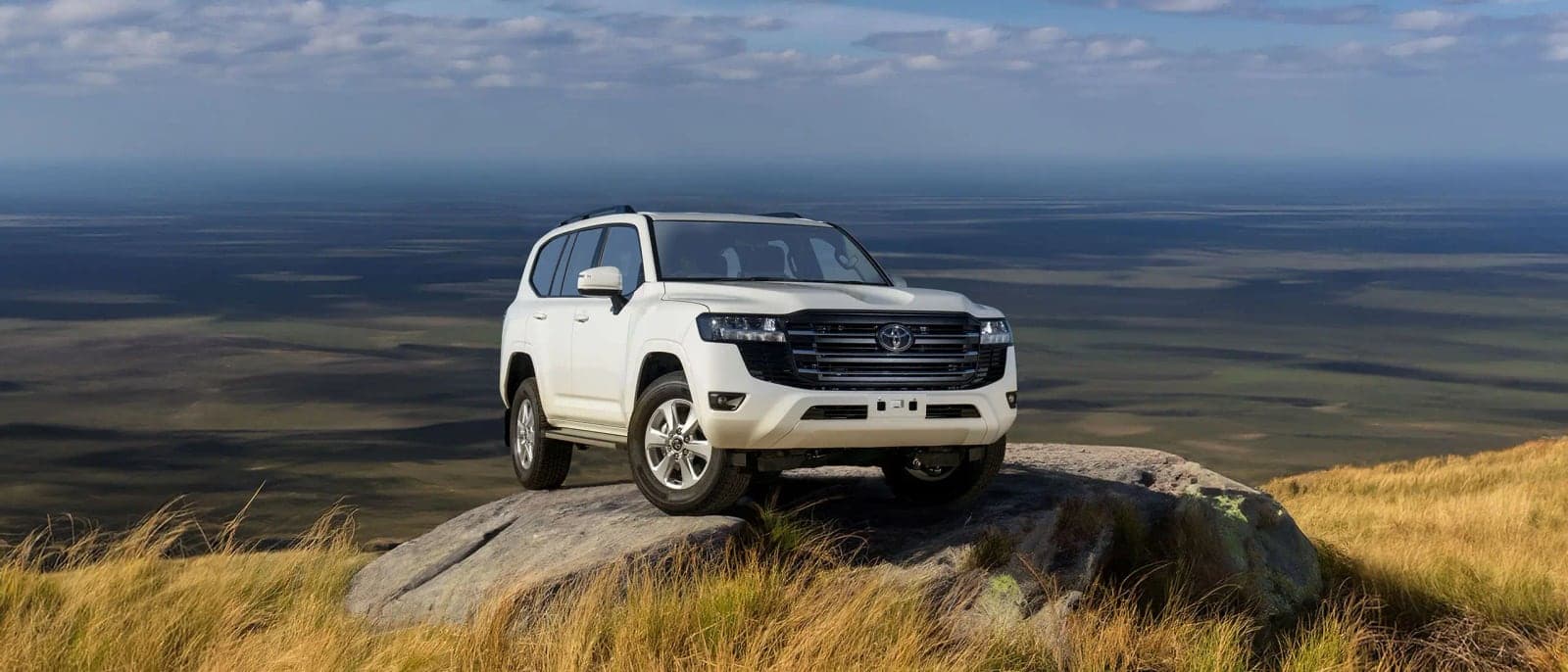 White Land Cruiser 300 parked on a rock outcrop above open plains