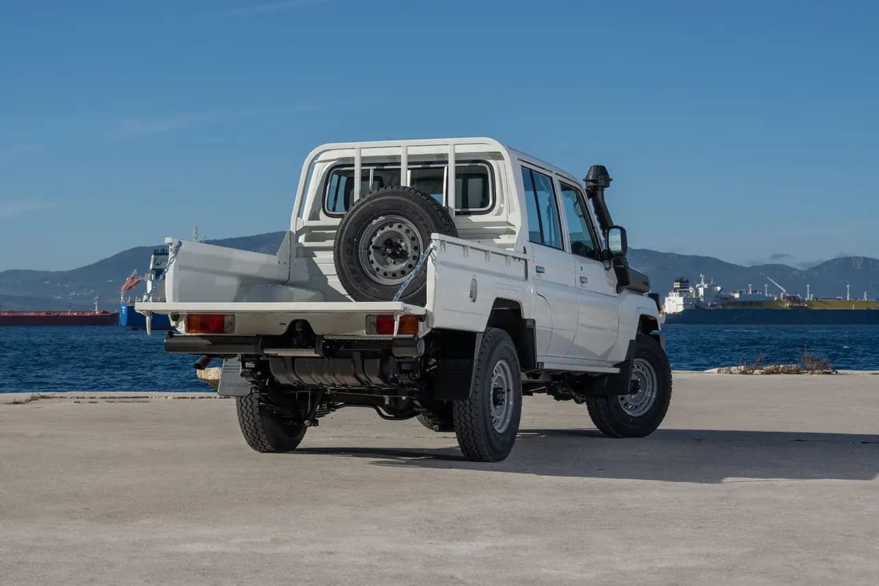 Land Cruiser 79 Double Cab rear three-quarter view with the tailgate lowered and spare wheel in the bed